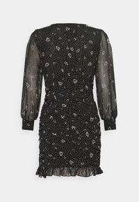 Black dress with sheer long sleeves, featuring a dotted pattern and heart shapes. Ruching at the waist and a frilled hem detail.