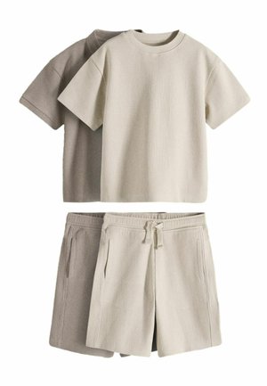 To sæt ribstrikkede kortærmede skjorter og matchende shorts i beige og lys brun lagt fladt på en hvid baggrund.