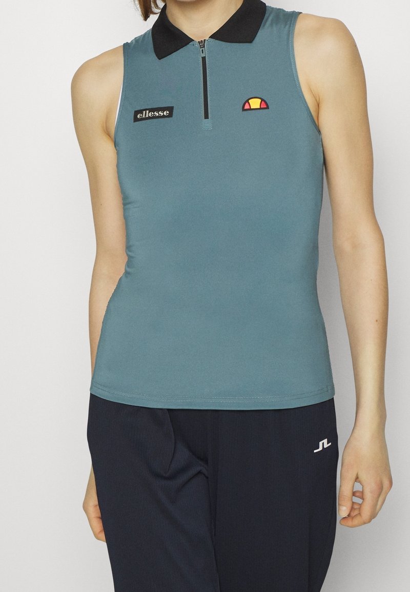 Ärmlös petrolblå polo-topp med svart krage, dragkedja framtill och broderad logotyp. Slät textur med minimala sömnadsdetaljer.