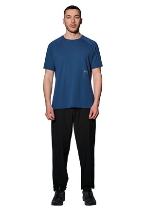 Blå kortærmet træningsshirt med en struktureret overflade og logo, parret med sorte løstsiddende bukser og mørke sko.