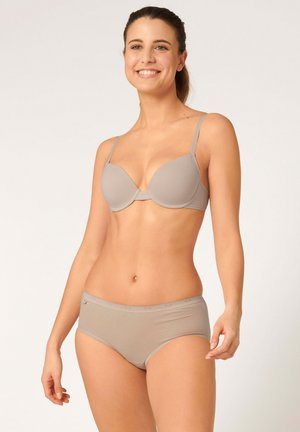 Reggiseno beige con coppe preformate e spalline regolabili abbinato a mutandine a boxer beige. Il materiale appare liscio e senza cuciture.