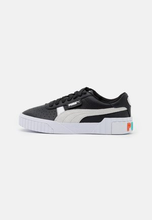 Baskets Puma basses noires et blanches avec bout perforé, semelle blanche et lettrage Puma coloré sur le talon.