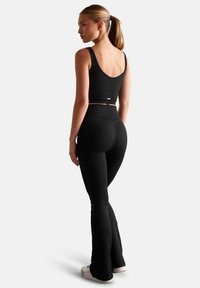 Zwarte geribbelde crop top en hooggetailleerde flared leggings. Glad, rekbaar materiaal met een aansluitend ontwerp en minimale merktekens.
