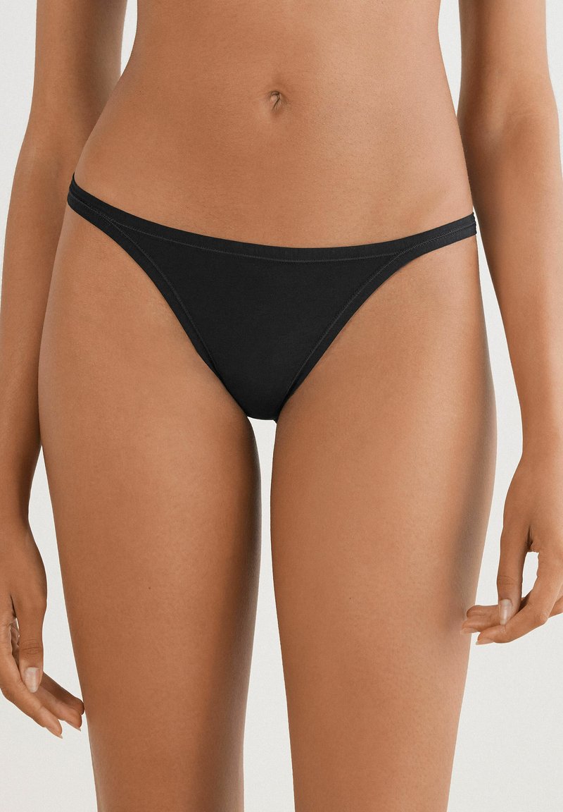 Zwarte stringonderbroek van zacht katoen met een dunne tailleband en minimale bedekking, met een gladde textuur en geen zichtbare patronen.