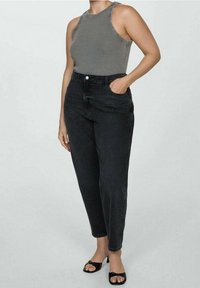Czarne jeansy w wysokim stanie o dopasowanym kroju, zestawione z szarym topem bez rękawów. Jeansy mają zapięcie na guzik z przodu oraz kieszenie.