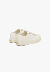 Sneaker in tela bianca sporca con occhielli metallici, lacci piatti e suole in gomma testurizzata. Caratterizzato da un piccolo logo sul tallone.