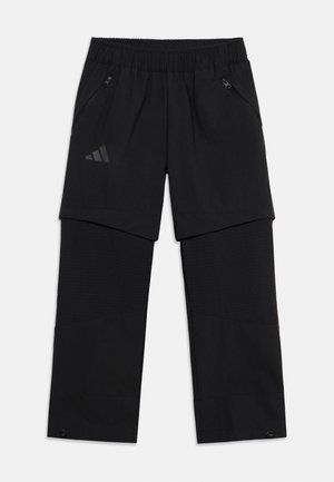 Melnas sporta bikses ar slāņveida dizainu, elastīgu vidukli, sānu kabatām ar rāvējslēdzējiem, Adidas logotipu uz kreisā augšstilba priekšpuses un regulējamām apakšmalām ar pogām.