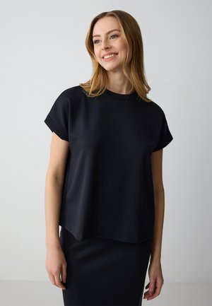 Top nero a maniche corte con scollo rotondo, realizzato in tessuto morbido. Il design presenta una vestibilità comoda e un orlo leggermente curvo.