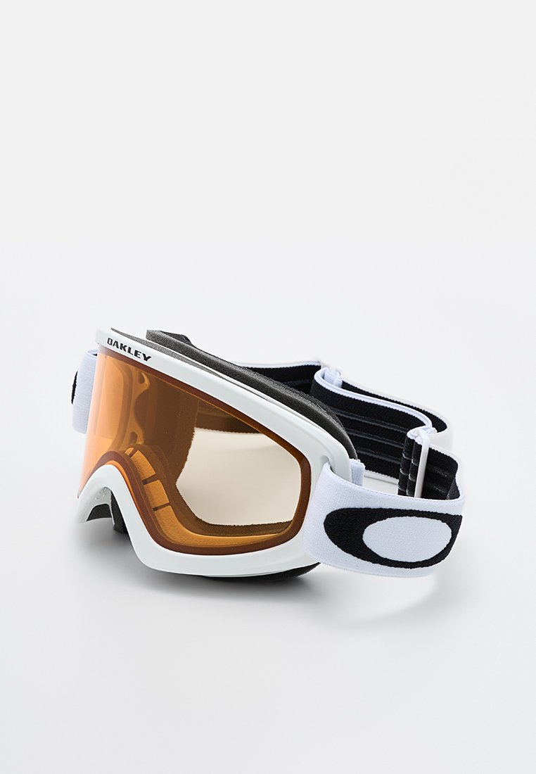 Gafas de esquí Oakley con un marco blanco, lente naranja y cinta negra. Presentan un forro de espuma y un diseño aerodinámico para mayor comodidad y visibilidad.