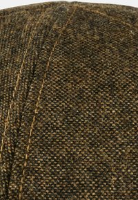 Braun gemustertes Gewebe mit einer strukturierten Webart. Das Material hat eine Mischung aus helleren und dunkleren Fäden, die ein gesprenkeltes Aussehen erzeugen.