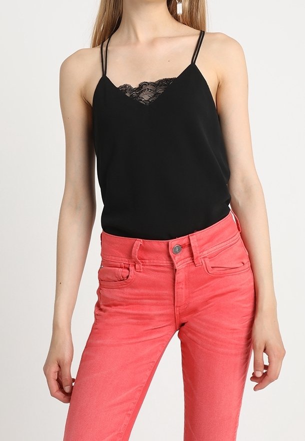 Svart satinlinne med spetsteknikk, parat med ljusrosa denimjeans. Linne har tunna axelband och en avslappnad passform.