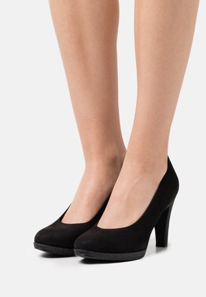 Chaussures à talons hauts en suede noir avec un bout rond, une surface lisse et un talon noir texturé. Design simple, sans accents ni motifs supplémentaires.