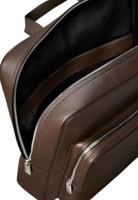 Borsa in pelle marrone con scomparti multipli. Presenta zip in argento, una texture liscia e un ampio interno. Fodera nera visibile all'interno.