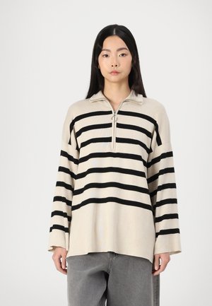 Pullover beige e nero a righe con colletto zip, caratterizzato da maniche lunghe e una vestibilità comoda. Realizzato in un morbido materiale a maglia.
