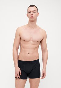 Svart bokser briefs laget av mykt stoff, med en tett passform og bred elastisk midje med merkevare. Glatt tekstur og enkelt design.
