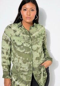 Košile s límcem a dlouhými rukávy, zelený tie-dye vzor, s kapsou. Měkká textura s kombinací světlých a tmavých zelených vzorů.
