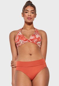 Top de bikini rojo con halter, patrón floral y diseño envolvente; combinado con un bikini de cintura alta rojo sólido con una cinturilla ancha.
