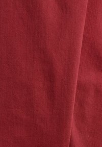 Tissu en coton d'un rouge profond, affichant une texture lisse avec un subtil motif de tissage diagonal. Le tissu tombe doucement sans embellissements visibles.