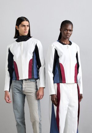 Jachete albe cu accente negre, albastre și maronii. Material neted, închidere cu fermoar, design scurt. Blugi din denim deschis și pantaloni albi completează ținutele.