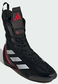 Black athletic shoe with a high-top design, textured material, red accents, and three white stripes on the side. Features a cushioned collar and lacing.