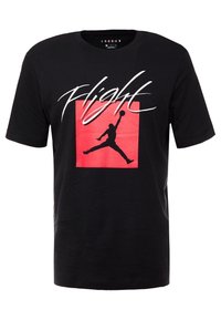 Camiseta de manga corta negra con un cuadrado rojo, silueta negra de un jugador de baloncesto saltando y texto en blanco "Flight" en el pecho.