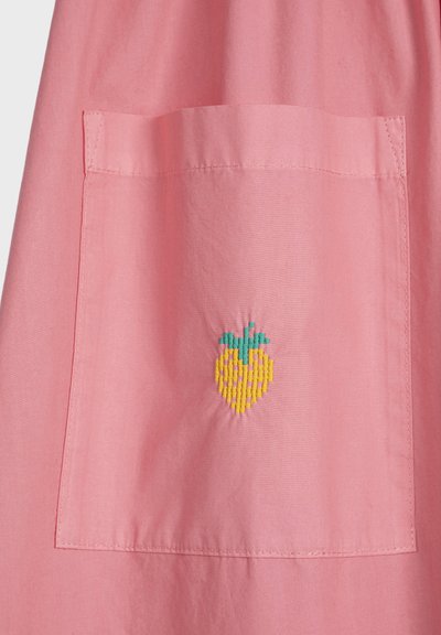 Poche en tissu rose avec une petite fraise jaune brodée au centre, surmontée de feuilles vertes.