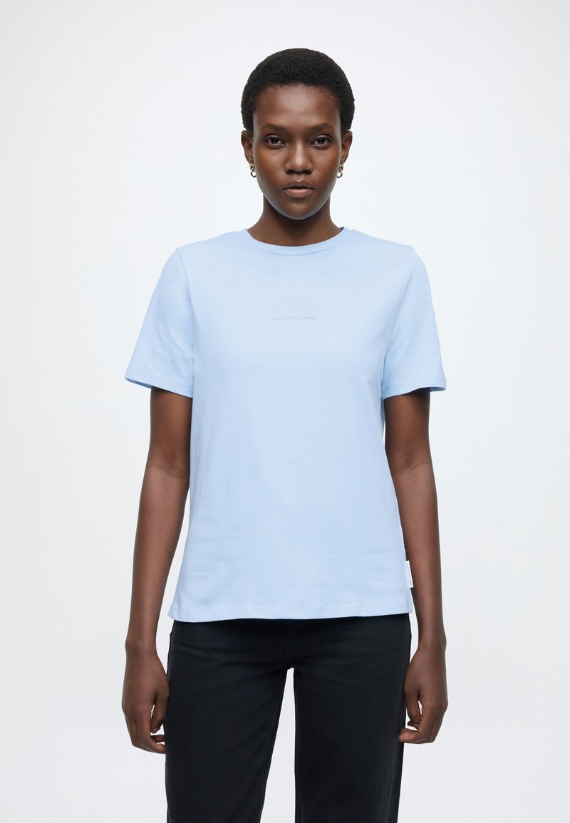 Απαλό γαλάζιο κοντομάνικο μπλουζάκι από μαλακό ύφασμα. Διαθέτει στρογγυλή λαιμόκοψη και μικρό λογότυπο μπροστά. Φοριέται με μαύρο παντελόνι.