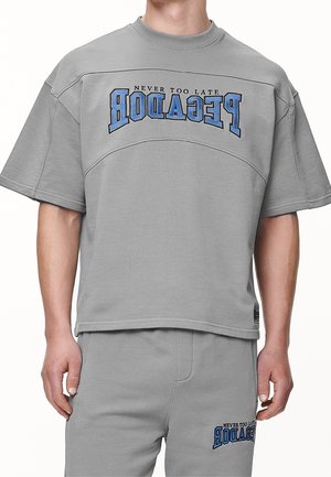 Grå kortærmet sweatshirt med fed blå tekst "NEVER TOO LATE" og "PEGADOR." Blødt stof med afslappet pasform og rund halsudskæring.