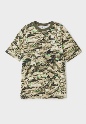 T-shirt de manga curta com padrão de camuflagem e detalhes em verde. Possui decote redondo e textura suave. O material parece leve.