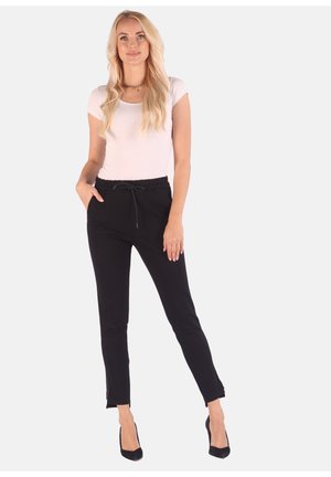 Black jogger pants with a drawstring waist, tapered legs, and side pockets, made from a soft, stretchy material. Paired with a fitted light top.