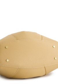 Krémová kožená kabelka s texturovaným povrchem, zaobleným tvarem a zlatými kovovými akcenty. Obsahuje viditelné švy a ochranné hroty.