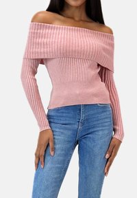 Rosa Rippenstrick-Pullover mit schulterfreiem Ausschnitt, langen Ärmeln und figurbetonter Taille, kombiniert mit blauen hoch taillierten Jeans.