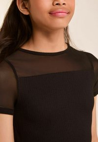 Schwarzes Oberteil mit einem strukturierten Rippen-Oberteil und transparenten, kurzen Ärmeln. Runder Halsausschnitt und figurnaher Schnitt betonen die Form des Kleidungsstücks.
