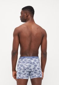 Blå mønstrede boxer briefs med palmebladsdesign, utstyrt med en ensfarget blå midje med "BJÖRN BORG" merkevare. Myk stoffkvalitet og tettsittende snitt.