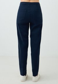 Pantaloni blu navy in cotone misto, con tasche posteriori e design a gamba affusolata, dotati di vita elastica e polsini alle caviglie.