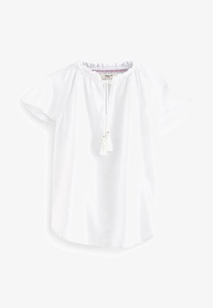 Blusa blanca de lino de manga corta con cuello fruncido y lazo delantero con pequeños flecos, mostrada sobre un fondo blanco.