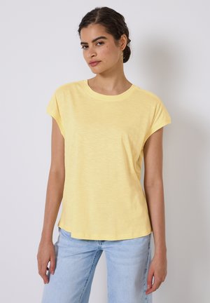T-shirt jaune à manches courtes avec un col rond, doté d'une coupe décontractée et d'un tissu doux et texturé. Assorti à un jean bleu clair.
