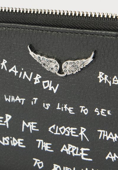 Cuir noir texturé avec ornement en forme d'aile argentée et texte en style manuscrit blanc incluant le mot "RAINBOW" et d'autres phrases dispersées.