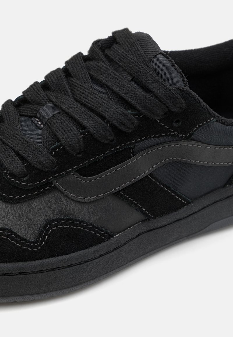 Baskets noires en mélange de suède et de cuir, avec des lacets plats noirs et des coutures contrastées. Design low-top avec une silhouette élégante.