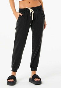 Sorte joggingbukser med elastisk talje, cremefarvet snor, sidelommer og tapered manchetter. Fremstillet af letvægts tekstureret stof.