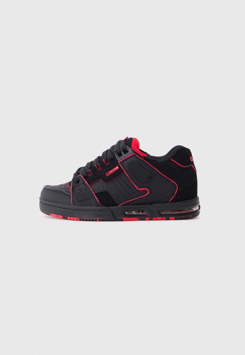 Black sneakers with red accents, featuring a textured upper, padded tongue, and air cushioning. The sole has a patterned design.
