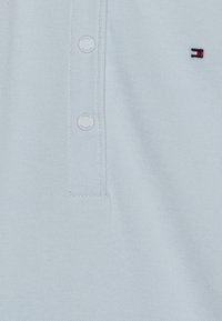 Jasnoniebieska koszulka polo wykonana z teksturowanej tkaniny, wyposażona w krótki kołnierzyk zapinany na guziki, subtelne logo oraz okrągłe guziki pokryte tkaniną.