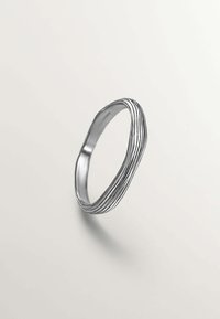 Anillo de plata con un diseño ondulado que presenta múltiples ranuras paralelas, textura suave y forma redondeada.