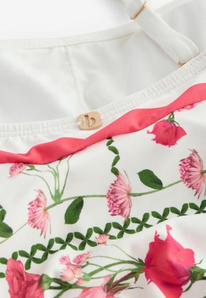 Stof met bloemmotief, met roze en groene rozen op een witte achtergrond, afgewerkt met een koraalrand en een gouden logoaccent.