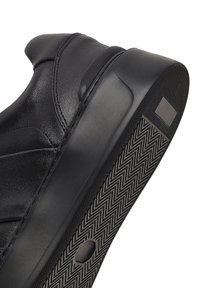 Baskets noires en cuir lisse avec un bout arrondi, dotées d'une semelle extérieure texturée et d'un motif en zigzag pour une meilleure adhérence.