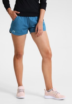 Pantalones cortos atléticos de malla azul con una cinturilla elástica, combinados con zapatillas texturizadas en rosa claro. El conjunto incluye una camiseta ajustada de manga larga negra.