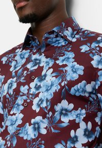 Bordeauxkleurig overhemd met knopen en een blauw bloemenpatroon, voorzien van een klassieke kraag en donkere knopen, gemaakt van een gladde stof met een lichte glans.