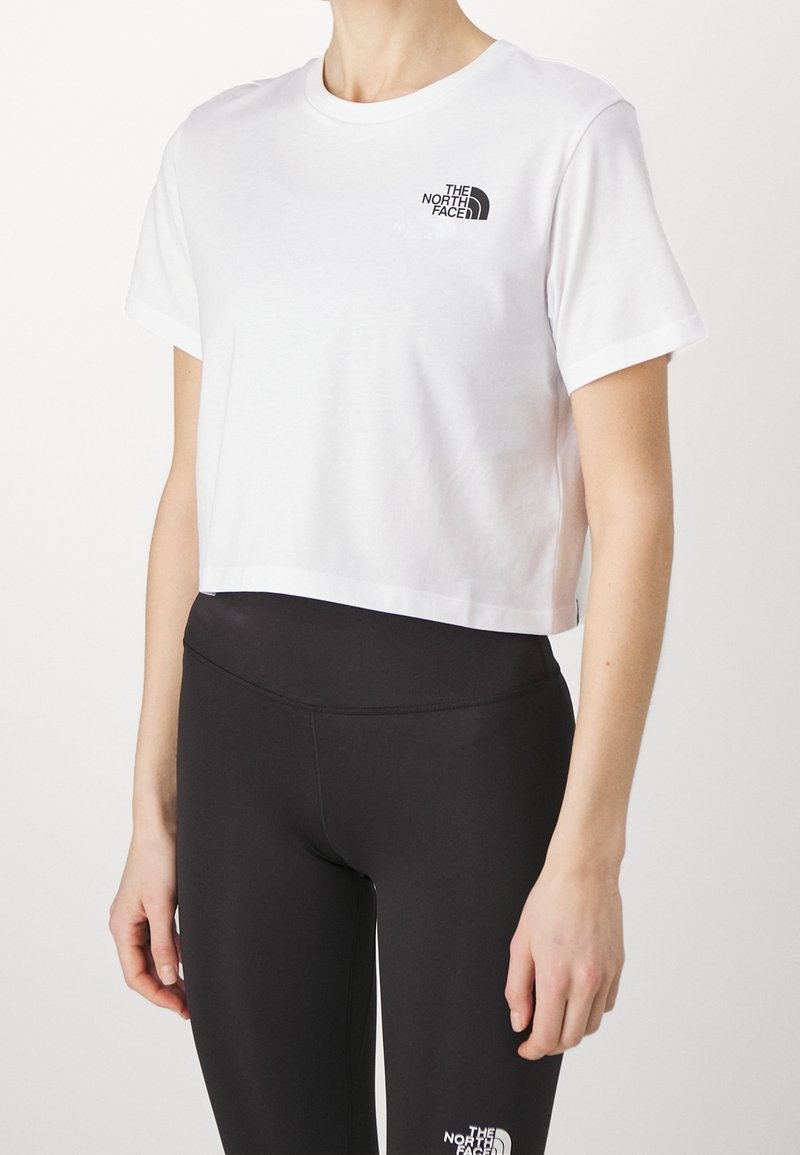 White cropped North Face t-shirt paired with high-waisted black North Face leggings on a person against a plain background.