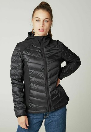 Zwarte geïsoleerde jas met een rits aan de voorkant, gequiltte bovenpanelen, elastische boorden en een capuchon, gecombineerd met blauwe jeans. Soepele oppervlakte textuur.
