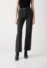 Sorte lige ben jeans lavet af denim, med høj talje, forlommer og kontrastsyning; parret med sorte hæle støvler.